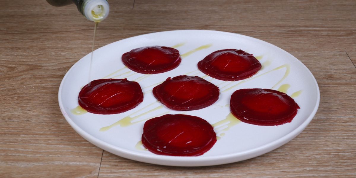 Verter aceite de oliva virgen extra en Raviolis de remolacha