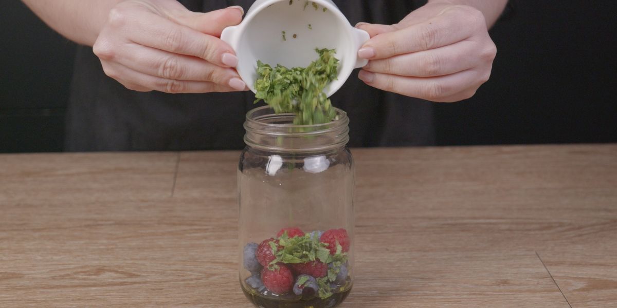 Añadir menta picada a Verter Aceite de oliva virgen extra en Vinagreta de frutos rojos