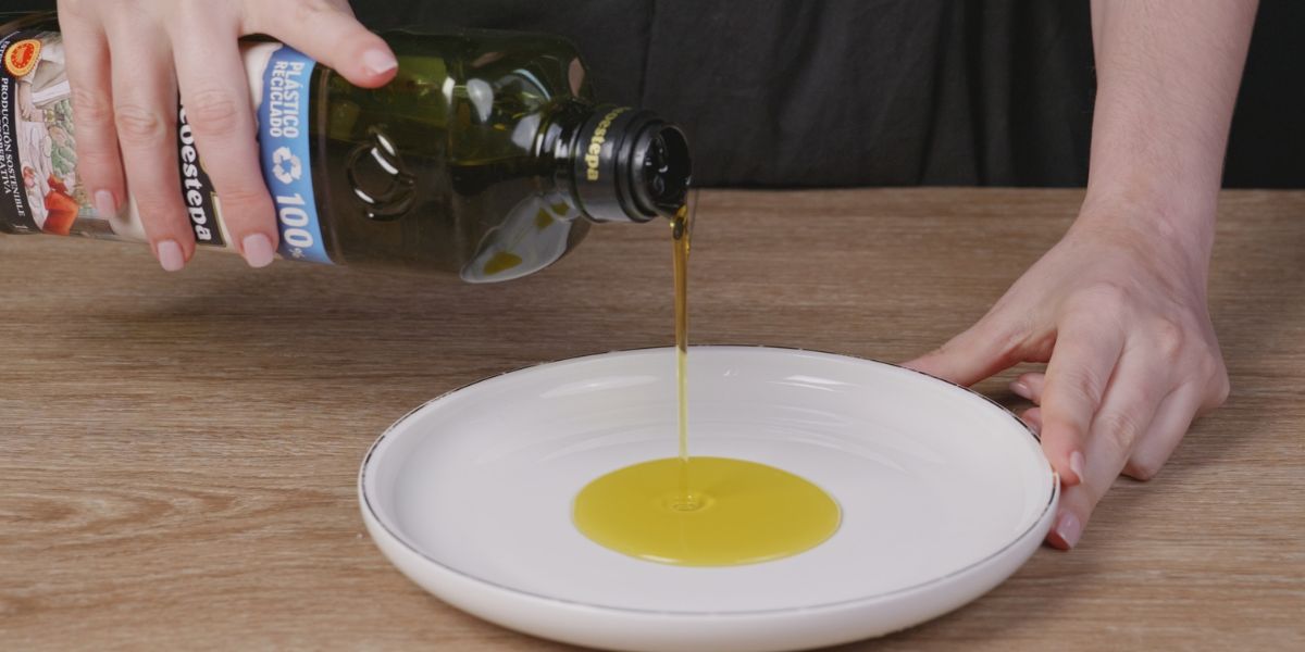 Verter aceite de oliva virgen extra en un plato para albóndigas de pollo y espinacas