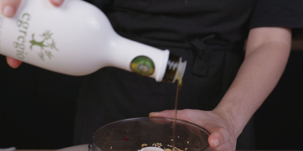 Verter aceite de oliva virgen extra para hummus remolacha