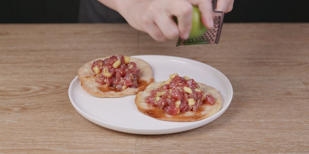Espolvorear lima sobre tartar de atún en tortas de aceite
