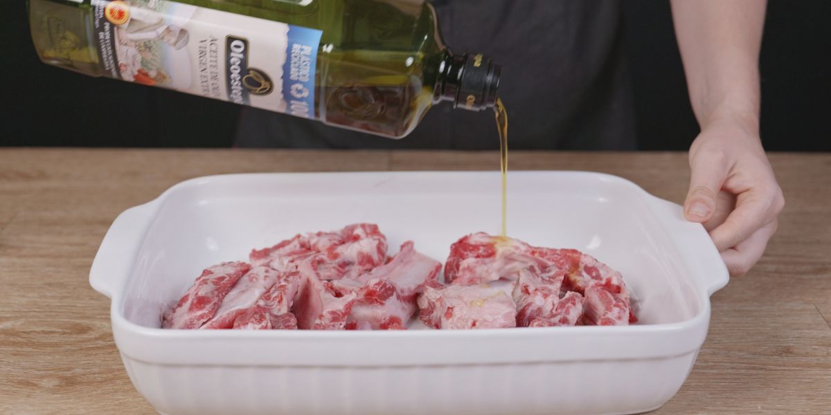 Verter aceite de oliva virgen extra sobre costillas al cajún