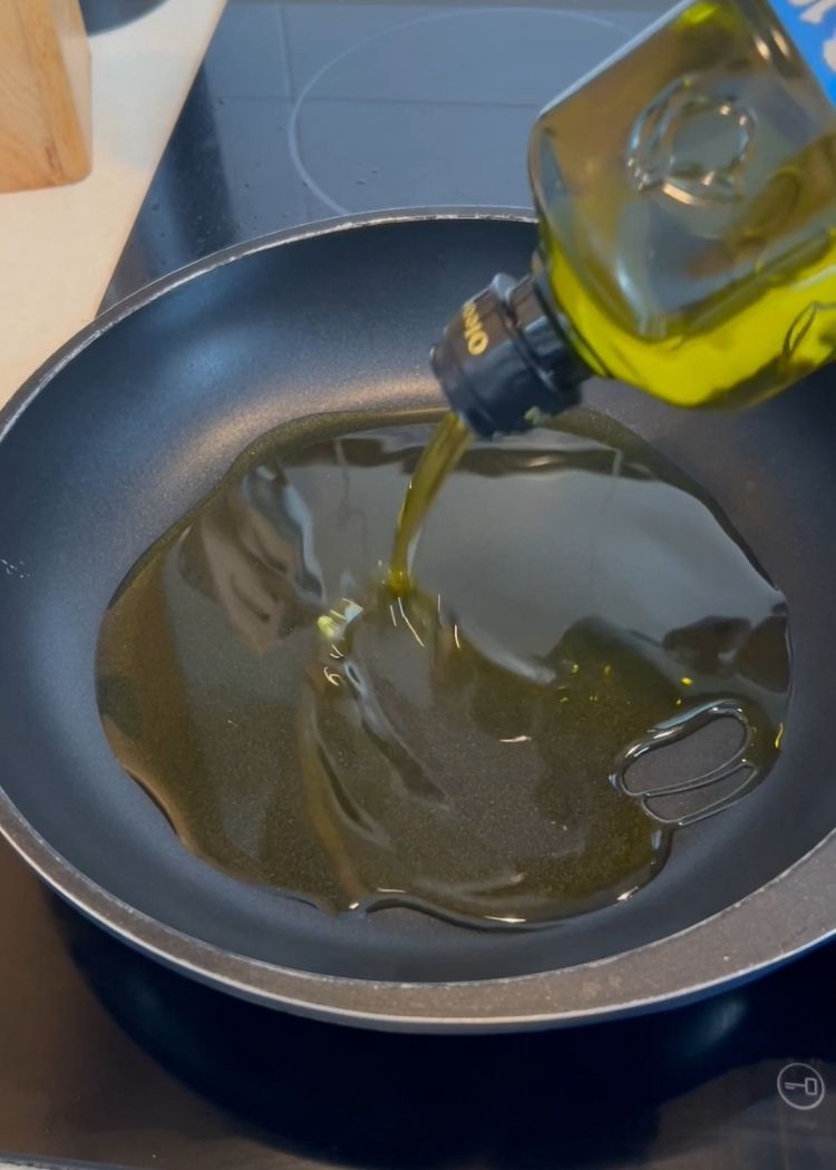 Echar aceite de oliva virgen extra a la sartén para hacer Ensalada de puchero con huevo frito