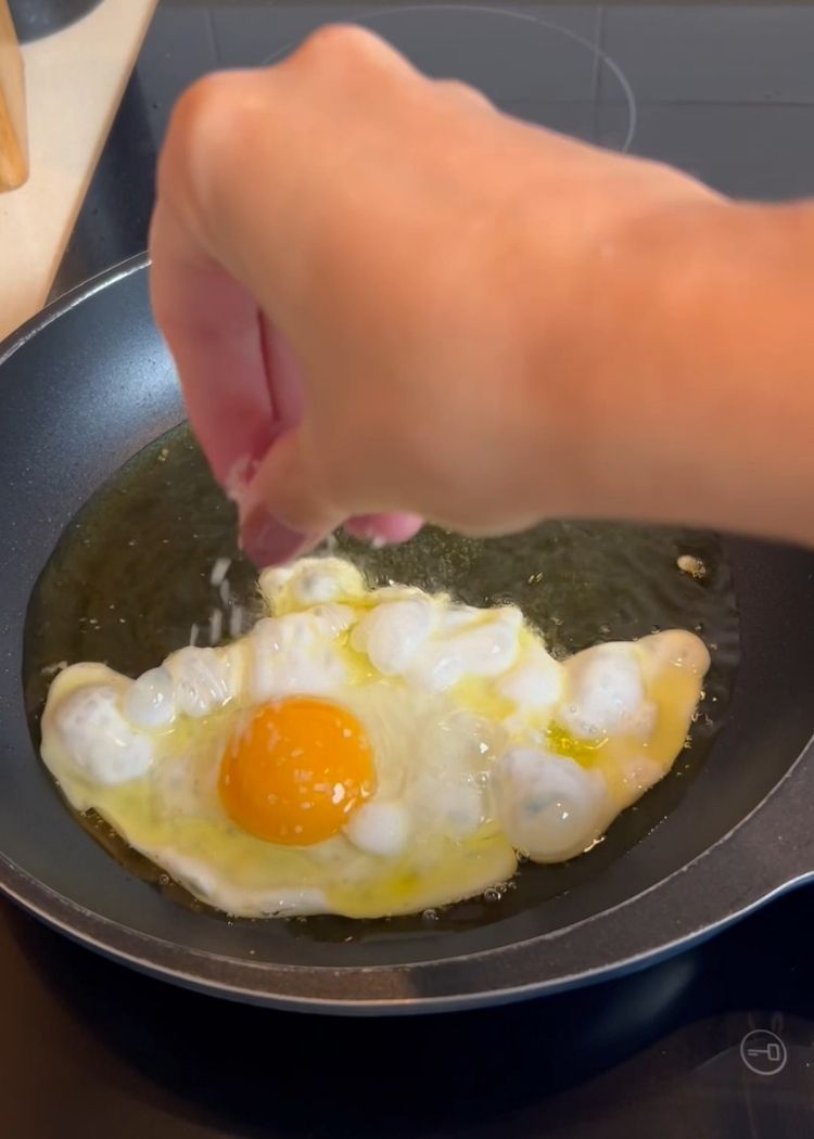 Añadir sal al huevo para hacer Ensalada de puchero con huevo frito