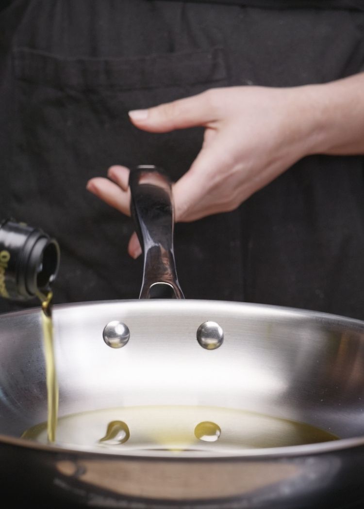 Echar chorreón de aceite de oliva virgen extra a la sartén Tostas con jamón y gulas