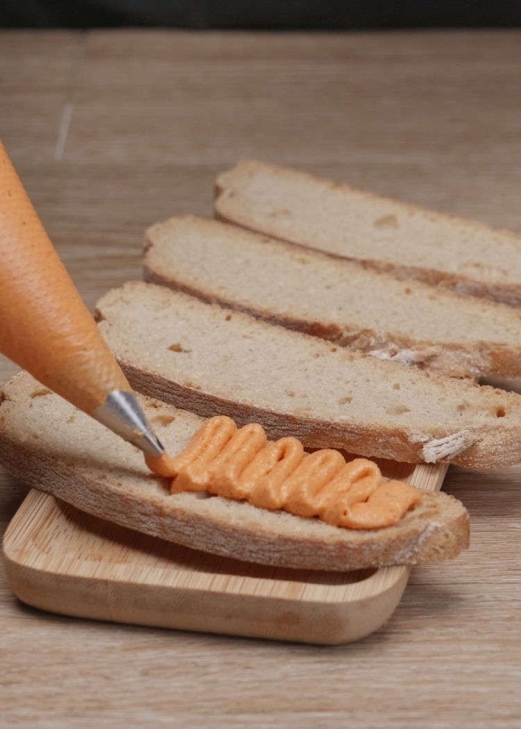 Poner crema de piquillos sobre pan