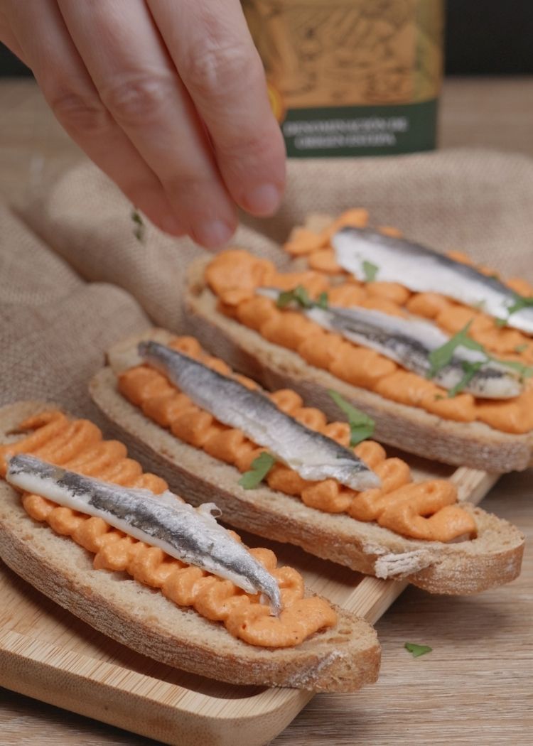 Añadir boquerón y perejil a canapé de piquillos
