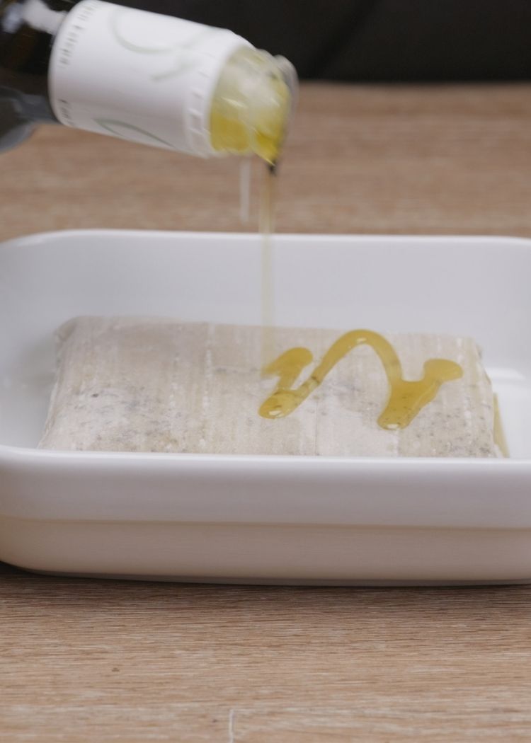Poner queso feta en bandeja y bañar con aceite de oliva virgen extra