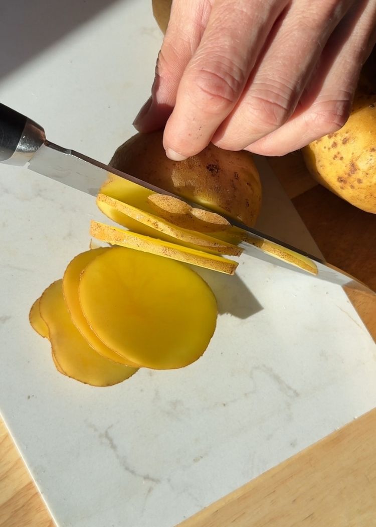 Cortar patatas para huevos rotos con patatas y chalotas al horno