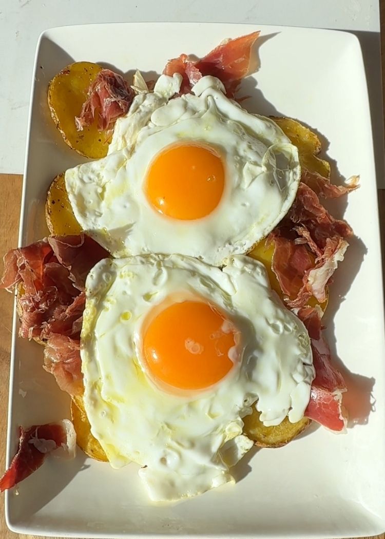 Cocinar y añadir huevos a huevos rotos con patatas y chalotas al horno