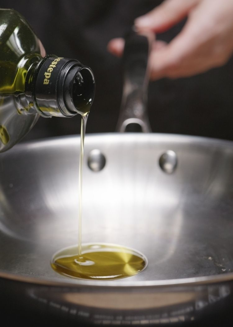 Echar aceite de oliva virgen extra a la sartén para pollo agridulce